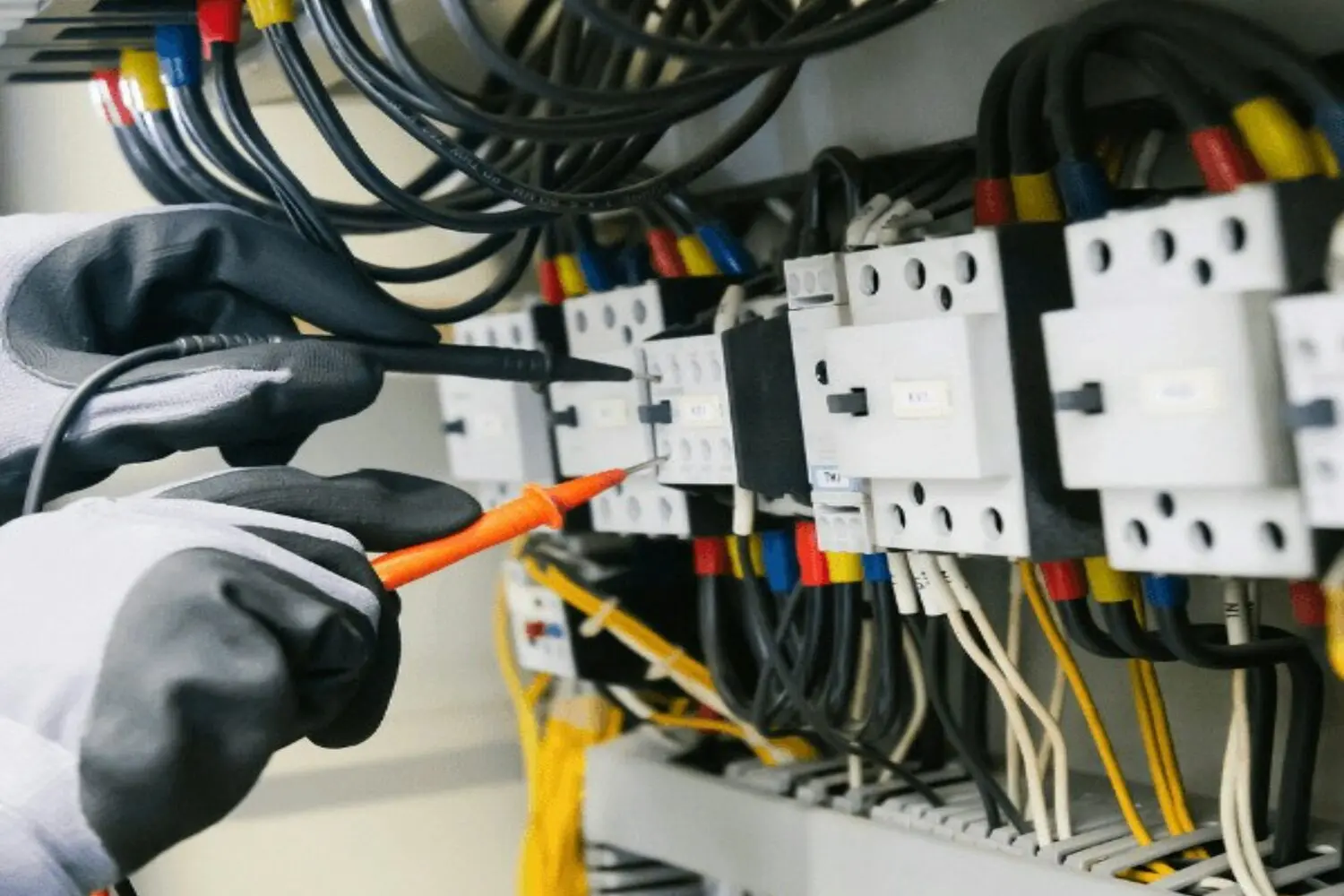 Electricista midiendo con un polímetro sobre los bornes de un cuadro eléctrico durante la revisión previa al certificado de instalación eléctrica