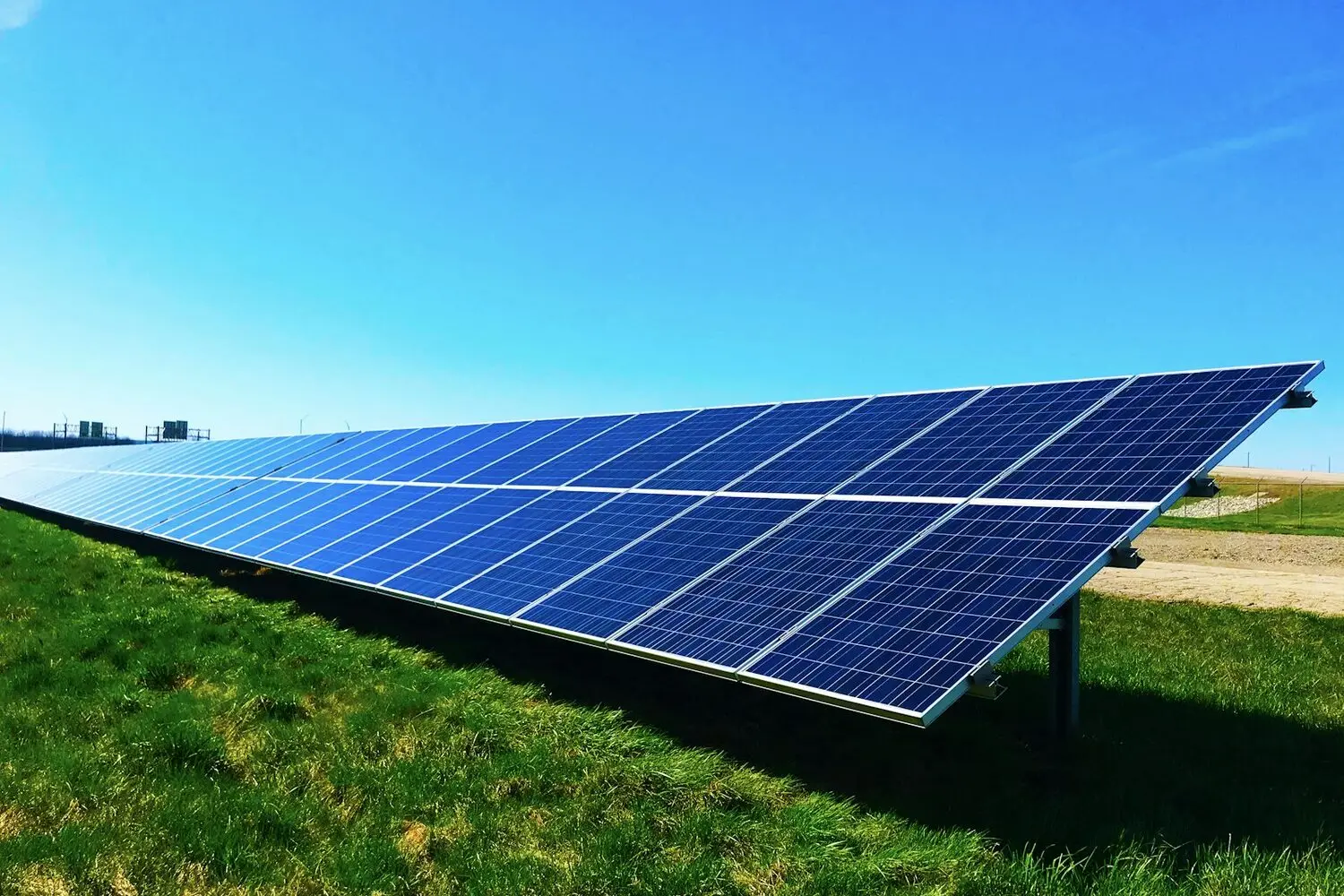 Fila de paneles solares produciendo energía bajo un cielo azul despejado